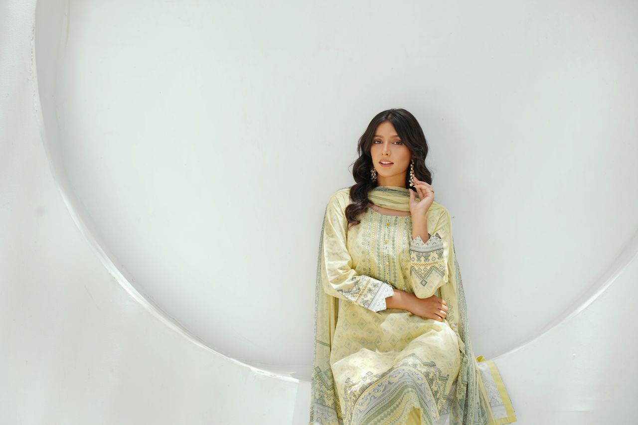 who-we-are South Asian woman in traditional dress poses elegantly against a white background.